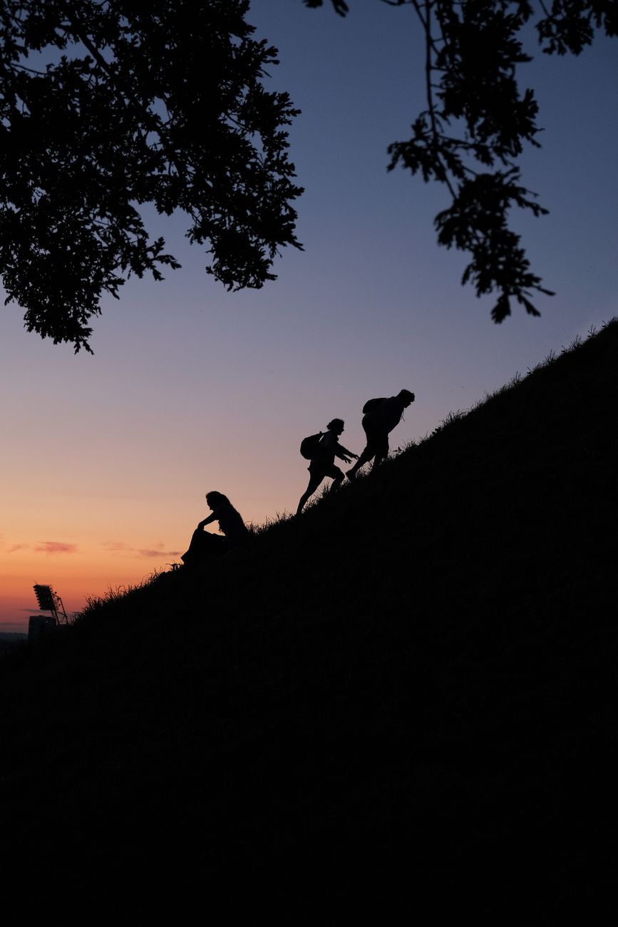 silhouettes hiking up hill at sunset